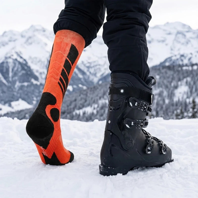 Orange cushioned thermal ski socks shown beside ski boots in the snow