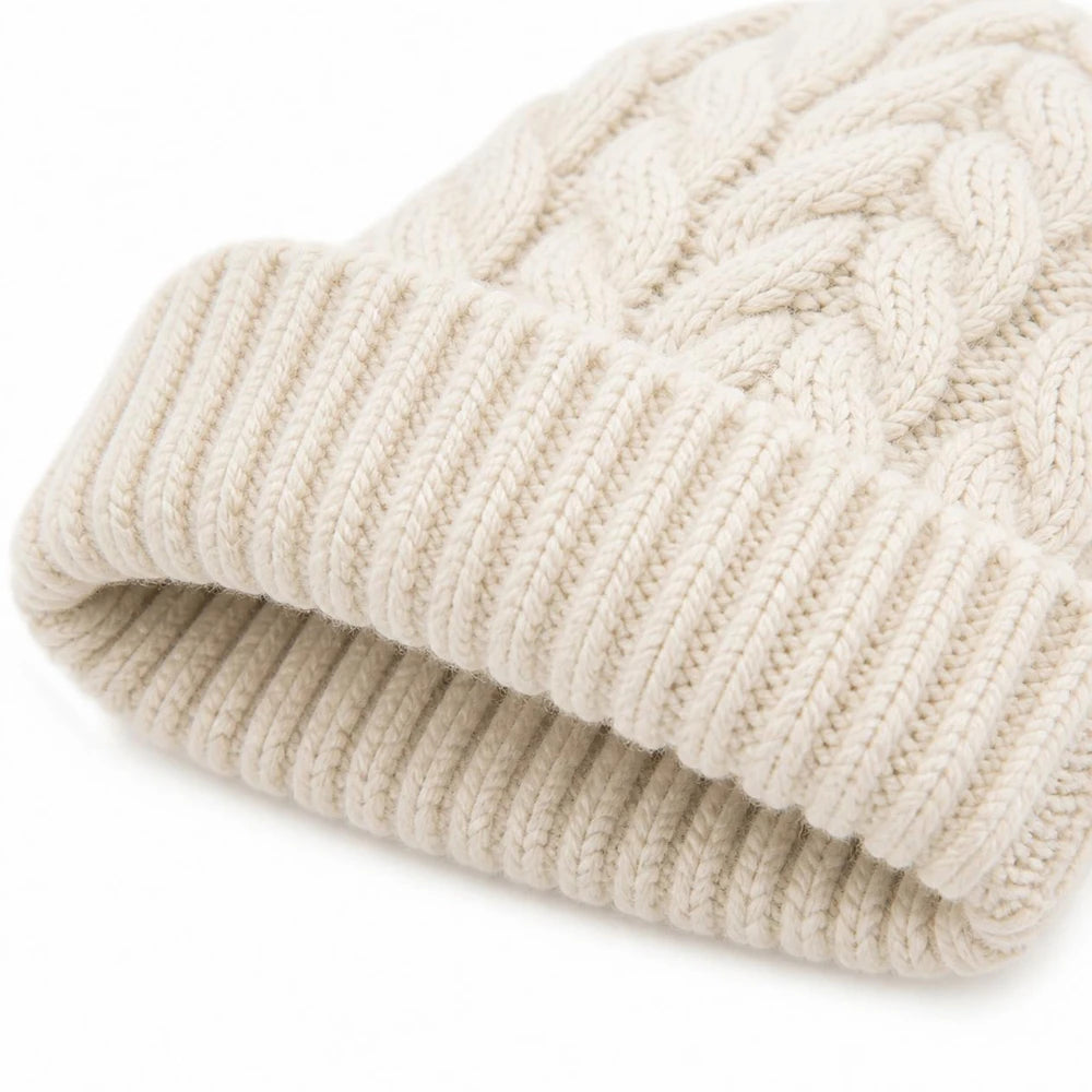 Close-up of the ribbed cuff on a white cable knit beanie showing elasticity and texture.
