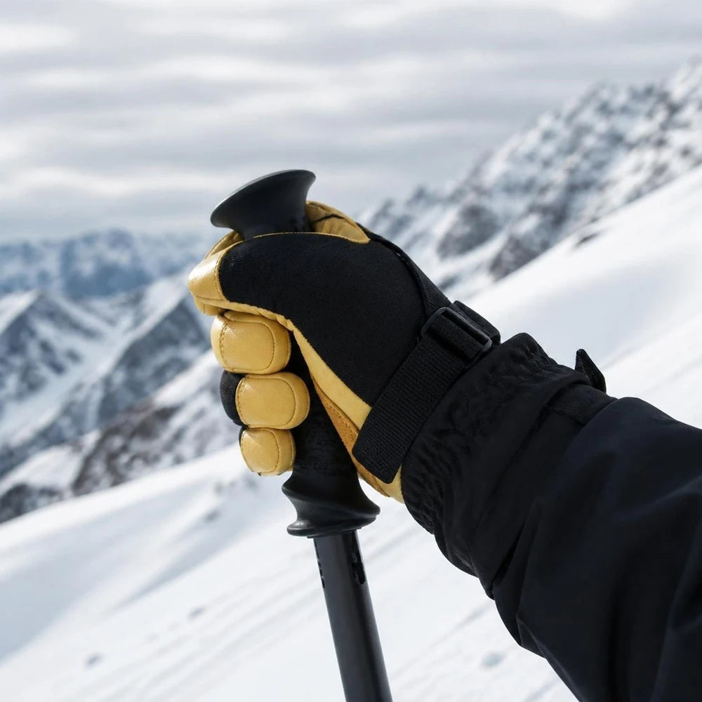 Skier wearing Vekap waterproof leather ski gloves holding a ski pole on a snowy mountain.
