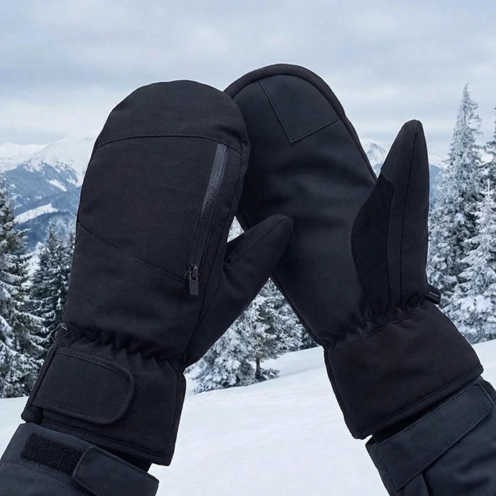 Wearing black waterproof ski mittens against a snowy mountain background.